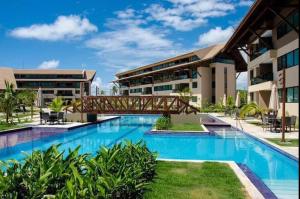 a bridge over a swimming pool in front of a building at Muro Alto Flat Nui Supreme in Porto De Galinhas
