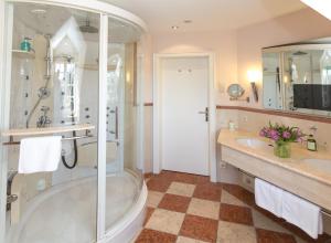 a bathroom with a shower, sink, and tub at Romantik Parkhotel Wasserburg Anholt in Isselburg