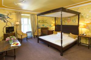 1 dormitorio con cama con dosel y sala de estar. en Romantik Parkhotel Wasserburg Anholt, en Isselburg