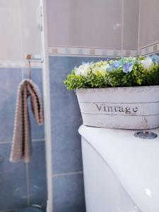a white planter with flowers on top of a toilet at Quinta dos Arcos Feel At Home in Armação de Pêra