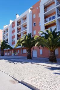 a row of palm trees in front of a building at Quinta dos Arcos Feel At Home in Armação de Pêra