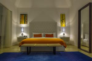 a bedroom with a bed with orange sheets and a mirror at Trident Hotel in Port Antonio
