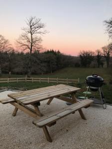 a picnic table with a grill next to a picnic at Gîte de charme Les Trois Chênes in Augères