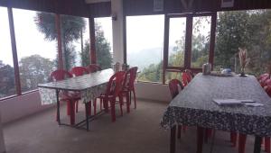 a dining room with two tables and chairs and windows at Vamoose Sinkawli Homestay in Takdāh