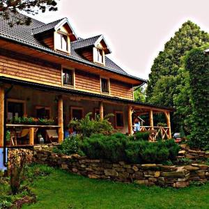 a large wooden house with a stone wall at Siedlisko Zakucie in Jaśliska