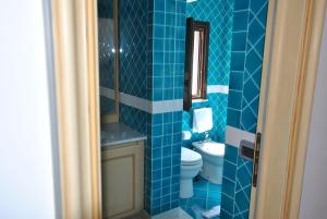 a blue tiled bathroom with a toilet and a sink at SEI - Isola Lunga in Marsala