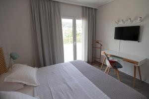 - une chambre avec un lit, un bureau et une télévision dans l'établissement Seaside Renovated Top Floor Apartment, à Saronida
