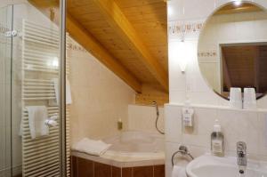 bagno con vasca, lavandino e specchio di Landhotel Guglhupf a Schwangau