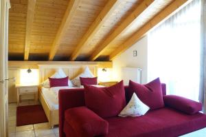 a bedroom with a red couch with pillows at Landhotel Guglhupf in Schwangau