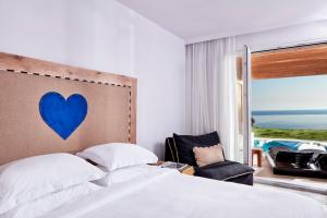 a bedroom with a bed with a blue heart on the wall at Myconian Imperial - Leading Hotels of the World in Elia Beach