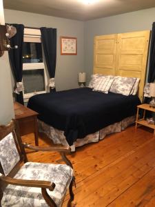 a bedroom with a bed and a chair and a window at Auberge d'Anjou-Sūrya Café in Petit Rocher