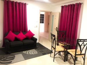 a living room with red curtains and a couch and chairs at Calliandras Apartment Complex in Kingstown