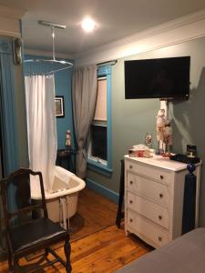Auberge d'Anjou-Cocooning Café في Petit Rocher: غرفة نوم مع حوض استحمام وكرسي وتلفزيون
