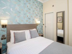 um quarto com uma cama com uma parede azul em OYO Bakers Hotel London Victoria em Londres