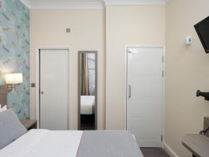ein Hotelzimmer mit einem Bett und einem Spiegel in der Unterkunft OYO Bakers Hotel London Victoria in London