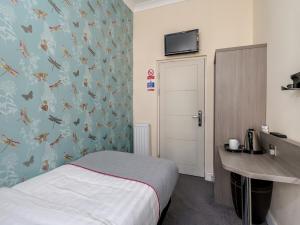 a bedroom with a bed and a desk and a wall with butterflies at OYO Bakers Hotel London Victoria in London