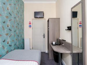 a bedroom with a bed and a desk and a mirror at OYO Bakers Hotel London Victoria in London
