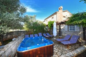 a hot tub in a yard with chairs and a house at Villas Barat by Istarski Dvori in Višnjan