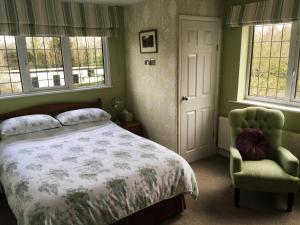 
a bedroom with a bed, chair, and a window at The Beeches Bed and Breakfast in Hinckley
