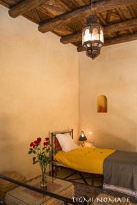 a bedroom with a yellow bed and a vase of flowers at Tigmi Nomade in Tahannout