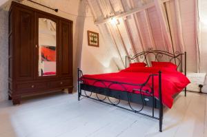 een slaapkamer met een bed met rode kussens en een spiegel bij Romantic 16th century workers house in Gent