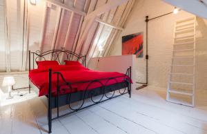 a bedroom with a red bed with red pillows at Romantic 16th century workers house in Ghent