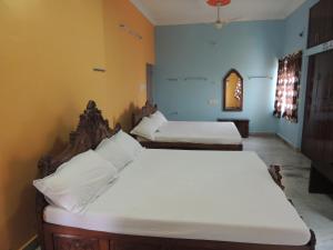 a bedroom with two beds with white sheets at Radha Party Hall in Kanchipuram