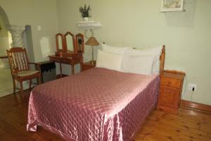 a bedroom with a bed and a table and a chair at Lajava Guest Lodge in Krugersdorp