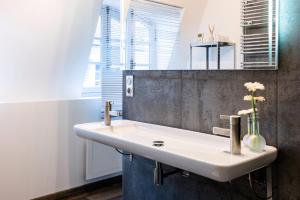 a bathroom with a sink and a vase with flowers at La Maison Blanche in Beaune +23 photos