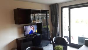 uma sala de estar com uma televisão de ecrã plano e uma janela em Fijn en gezellig App TIME-OUT, beg grond, Prive TERRAS, eigen KEUKEN, Dichtbij Strand en Vuurtoren, Incl verwarmd Hotel-ZWEMBAD em Hollum