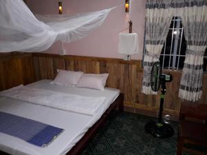 a bedroom with a bed and a window with curtains at Flower & Frog Homestay in Sa Ðéc