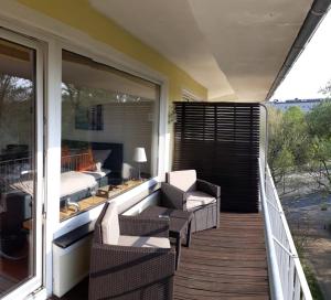 eine Veranda mit Stühlen und ein Bett auf einem Balkon in der Unterkunft Modern City Apartment with balcony and nice parc view in Bremen