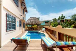 a patio with a pool and chairs and a house at Mirasol Villa in Placencia