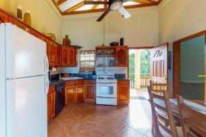 a kitchen with wooden cabinets and a white refrigerator at Mirasol Villa in Placencia