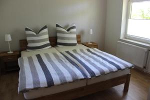 a bedroom with a bed with striped pillows and a window at Ferienwohnung Sannhoff in Schneverdingen