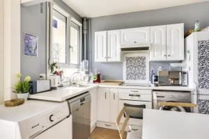een witte keuken met witte kasten en een wastafel bij Charming apartment with terrace by Weekome in Parijs