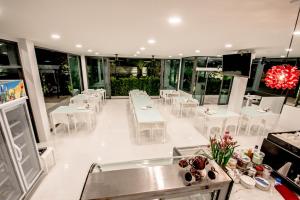 uma sala de jantar com mesas brancas e cadeiras brancas em Baan Yamoo Ranong em Ranong