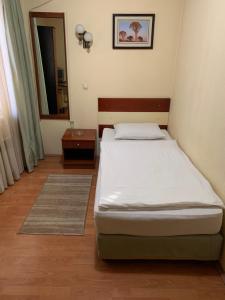 a small bedroom with a bed and a mirror at Hotel Ilinden in Strumica