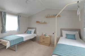 un dormitorio con dos camas y una mesita de noche y una cama sidx sidx sidx sidx en Belle Aire Holiday Park, en Hemsby 28 fotos más