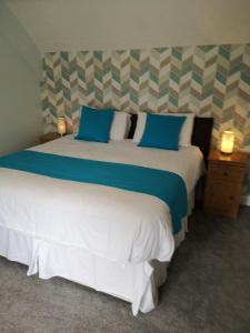a bedroom with two beds with blue and white pillows at Y Giler Arms in Pentrefoelas