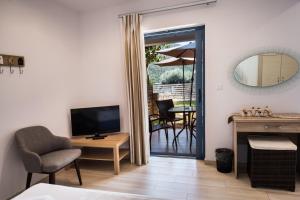 ミクロス・ギアロスにあるIlianthos Apartments & Roomsのリビングルーム(テレビ、テーブル、椅子付)