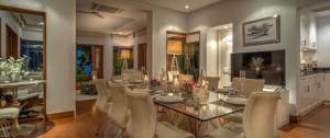 a dining room with a glass table and white chairs at Villa Macaque and Villa Languor in Railay Beach