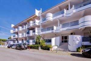 ein großes weißes Gebäude mit davor geparkt in der Unterkunft Ella - Fantastic apartment - Vilamoura in Vilamoura