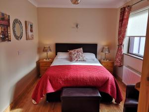 um quarto com uma cama grande e um cobertor vermelho em Mount Edward Lodge em Grange