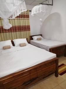 two beds in a room with white sheets at BAS Balcony in Anuradhapura