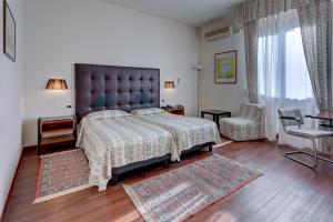 una camera con un grande letto e una sedia di Hotel Massimo d'Azeglio a Montecatini Terme