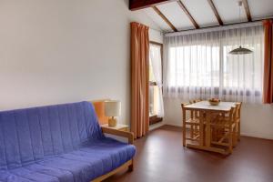 a living room with a blue couch and a table at Le Village Vacances de Mimizan Plage in Mimizan-Plage