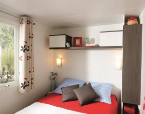 a bedroom with a bed with a red blanket and a window at Camping la Croix du Sud in Saint-Tropez