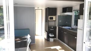 a small kitchen with black cabinets and a microwave at Camping la Croix du Sud in Saint-Tropez
