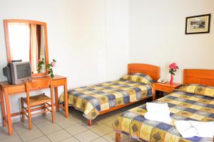 a room with two beds and a desk with a tv at Evia Studios in Loutra Edipsou